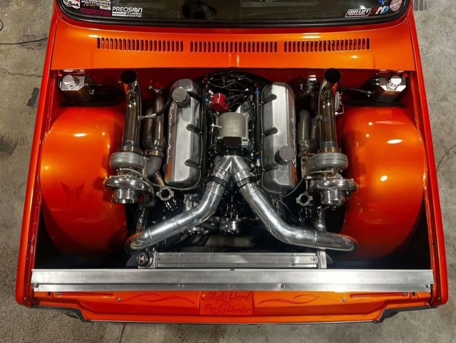 Twin-turbo LS engine bay with polished intake piping in an orange car