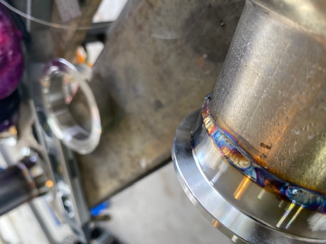 Close-up TIG weld bead on a stainless steel exhaust flange